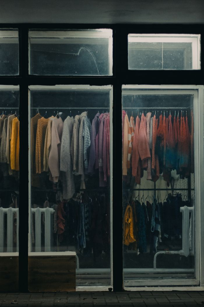 A vibrant clothing display in a store window featuring a variety of sweaters.