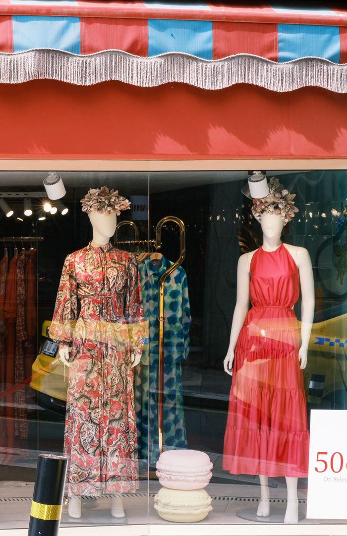Colorful boutique window showcasing mannequins dressed in elegant summer fashion.