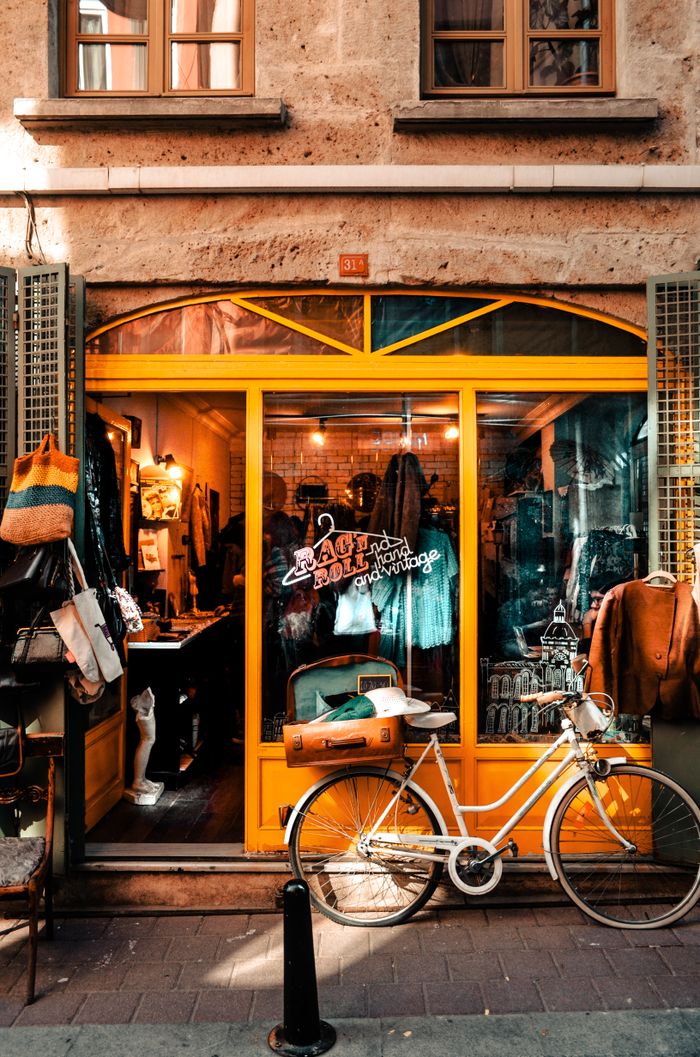 Exterior of old stone house and bright shop with big windows and bicycle on pavement