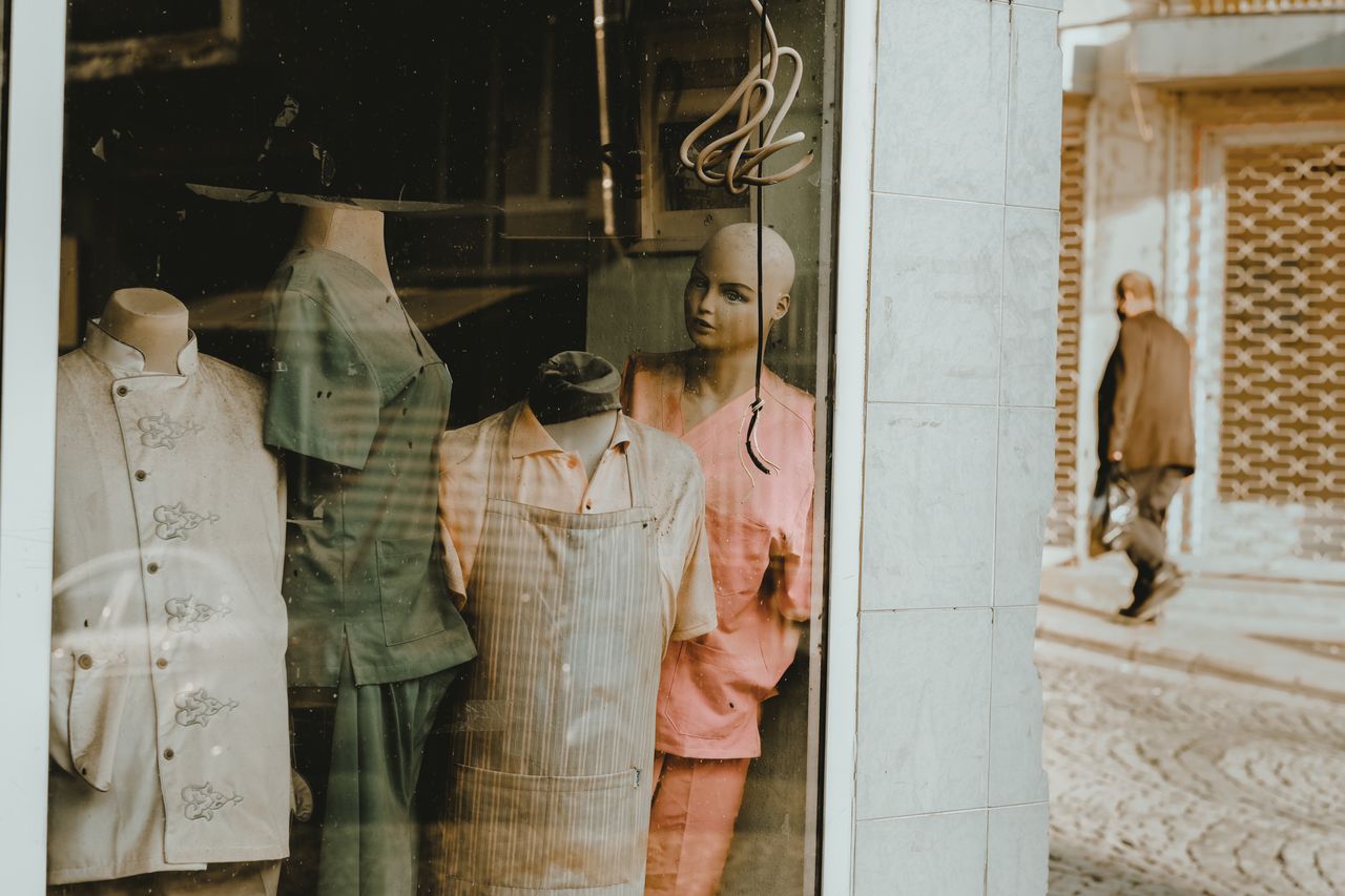 A shop window with mannequins displaying vintage clothing under a warm light.